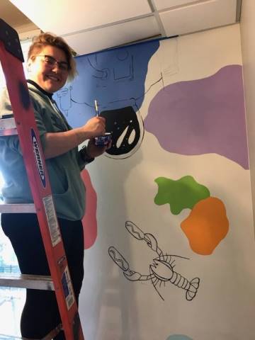 Washington High School faculty and students hand-paint their mural in Dax's Playroom at the Peoria Ronald McDonald House® in Peoria, Illinois.