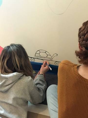 Washington High School faculty and students hand-paint their mural in Dax's Playroom at the Peoria Ronald McDonald House® in Peoria, Illinois.