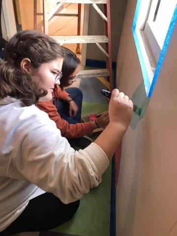 Washington High School faculty and students hand-paint their mural in Dax's Playroom at the Peoria Ronald McDonald House® in Peoria, Illinois.